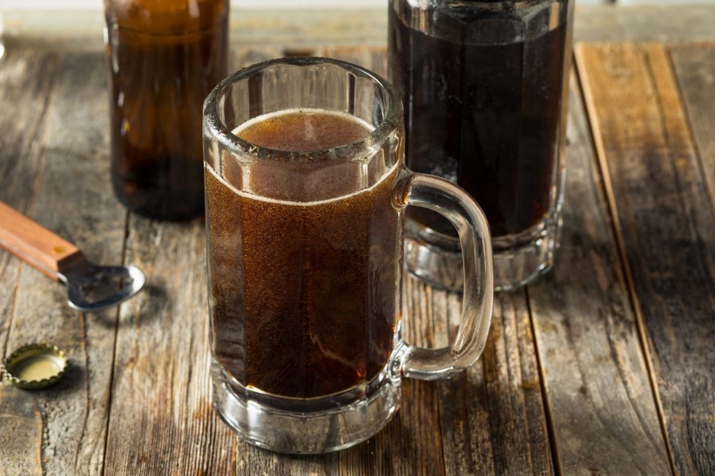 three glass mugs filled with root beer
